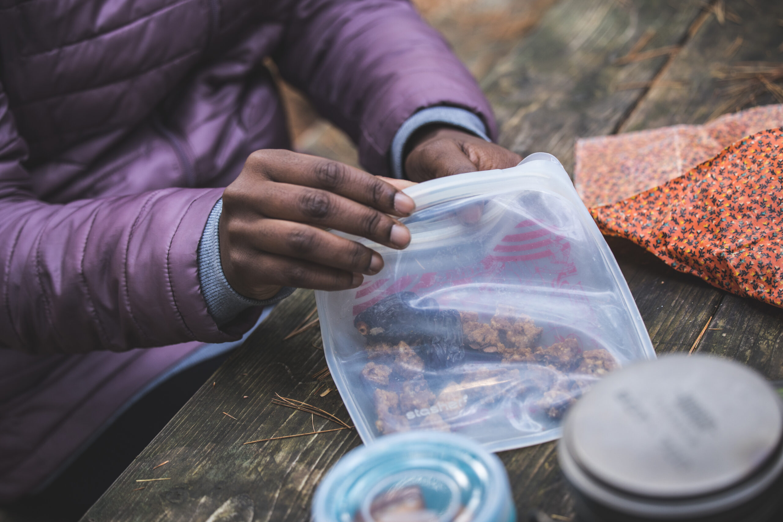 personne dont on voit uniquement les mains prenant des noix dans un sac en plastic posé sur une table